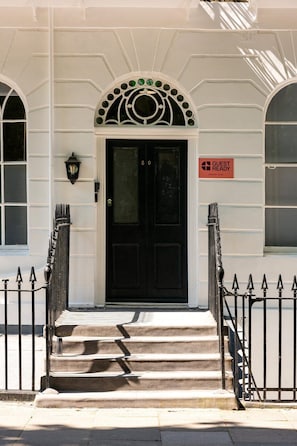 A black door with a 'GUEST READY' sign, a white building facade, and a black metal gate. - GuestReady - Stylish Double En-Suite in London (London)