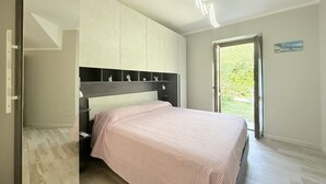 A bedroom with a bed, a wardrobe, a nightstand, and a door leading to a balcony. - S378 - Sirolo, new one-bedroom apartment with garden and parking (Sirolo)