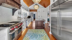 A kitchen with stainless steel appliances, wooden cabinets, and a chandelier. - ~HELLO GORGEOUS~ Soak up the sun, swim in the pool, or relax in the jacuzzi! (Key West)