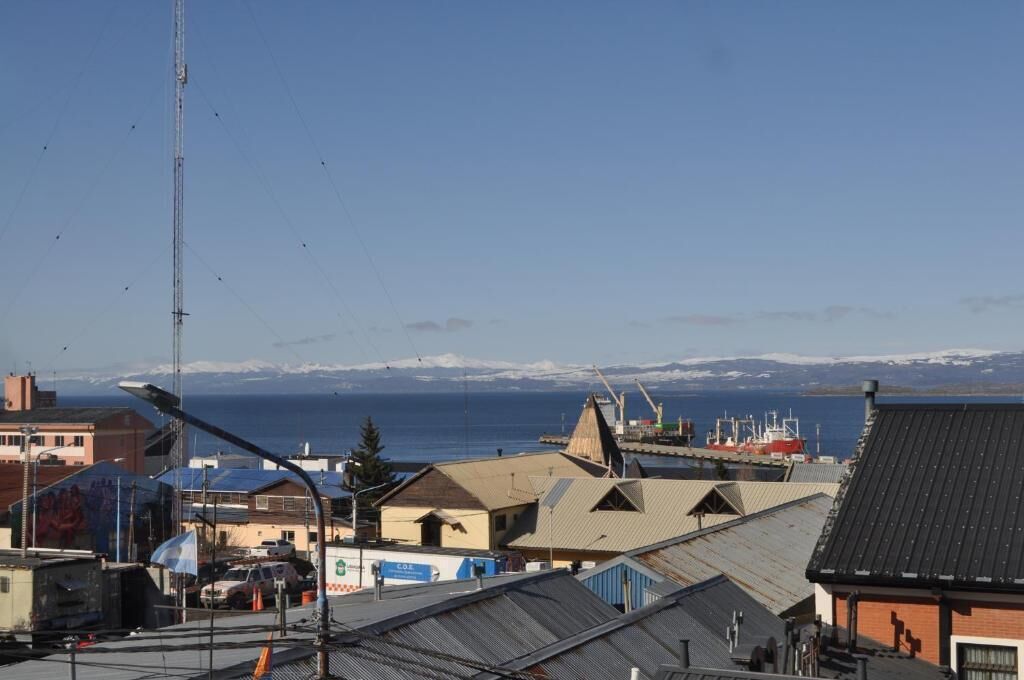 A coastal town with a clear view of the sea and snow-capped mountains in the distance.