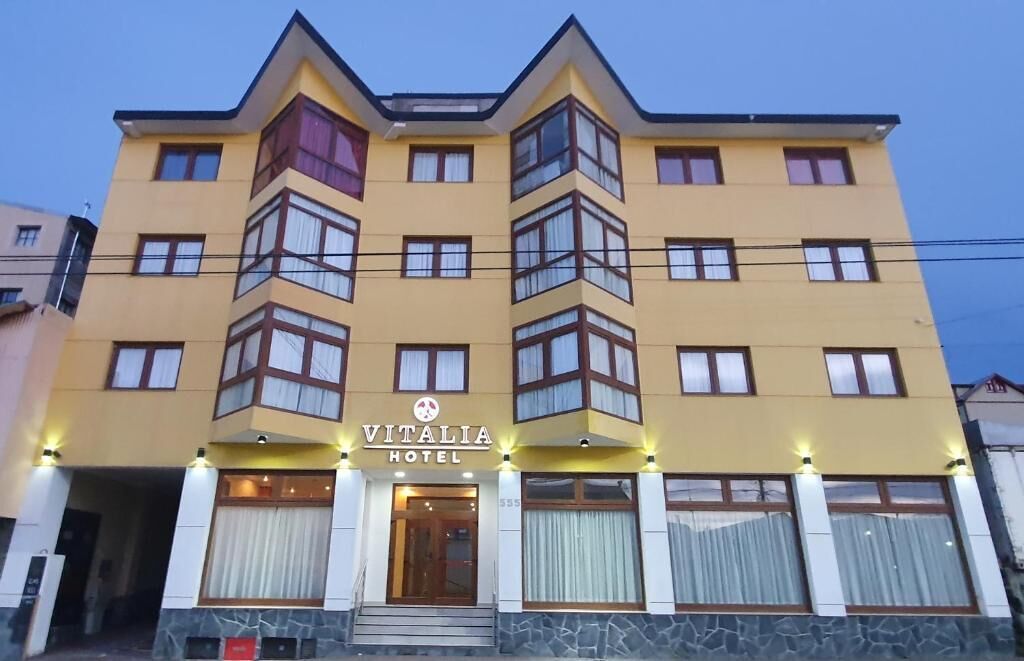 A multi-story hotel with a yellow facade, large windows, and a sign reading 'VITALIA HOTEL.'