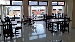 A dining area with multiple tables and chairs, large windows with views of the outside, and a clean, reflective floor. - Hotel Vitalia (Ushuaia)