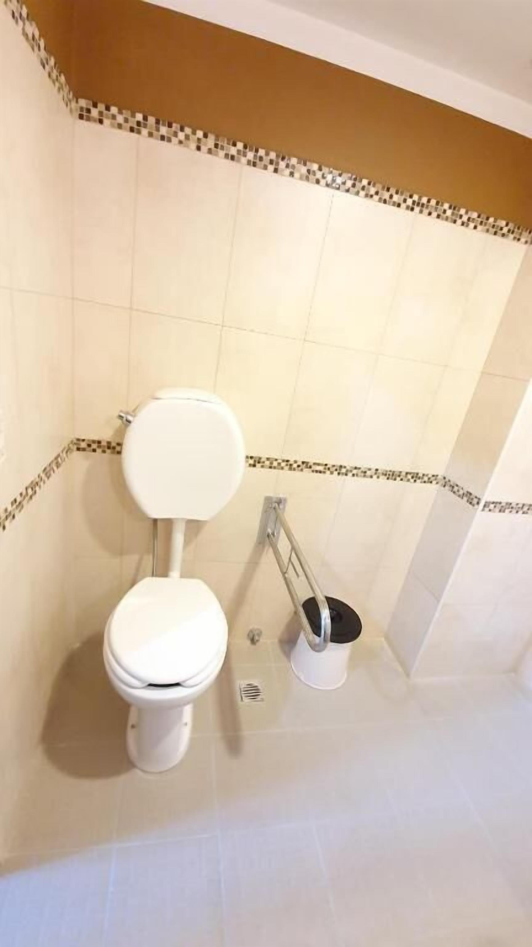 Casa de banho com sanita, bidé e barra de apoio.