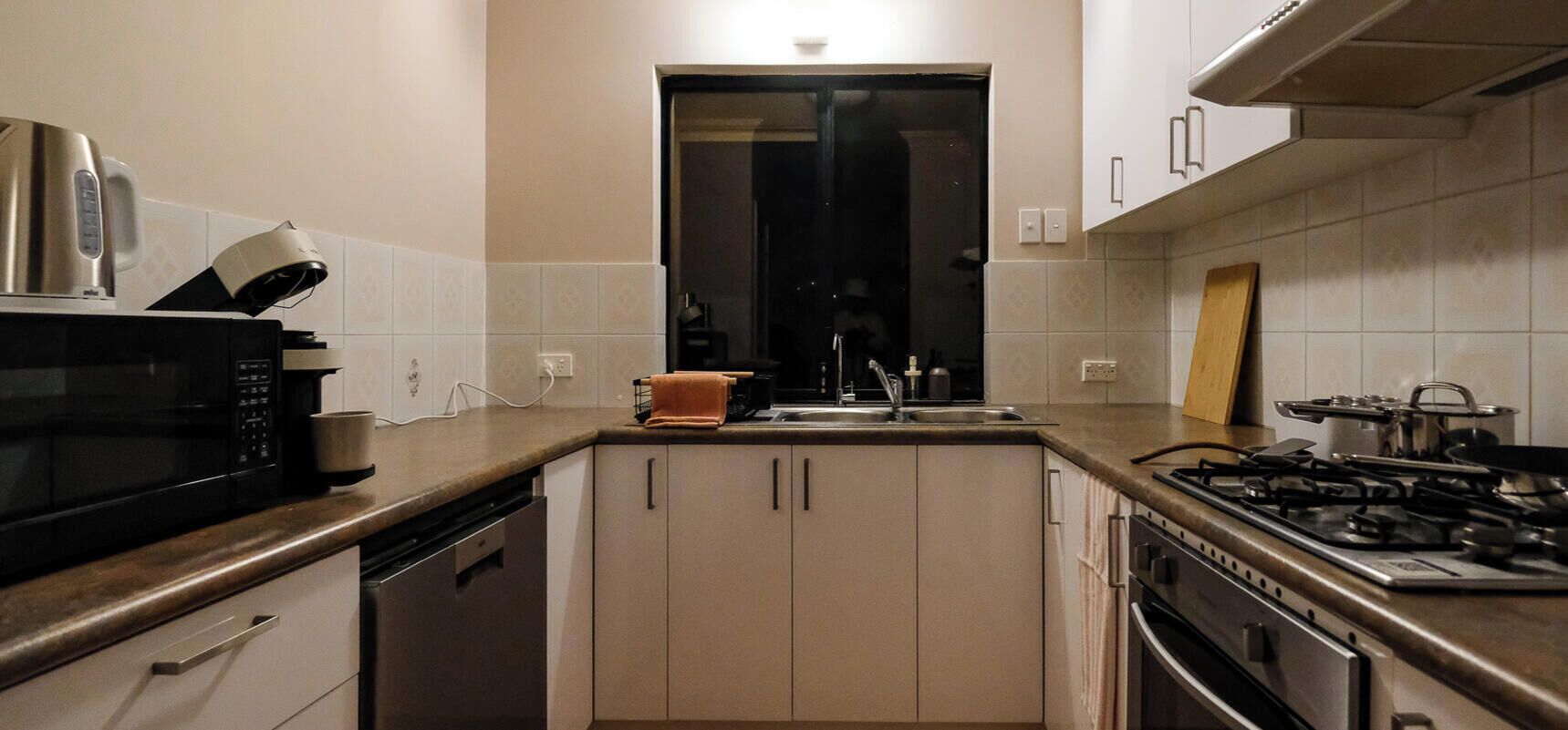 A kitchen with a microwave, stove, sink, and cabinets.