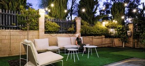 An outdoor seating area with a sofa, chairs, and a table, surrounded by a brick wall and greenery. - 3 BR Urban Retreat w/ Private Garden - Work Ready near CBD, Beach, Golfs & Malls (Nollamara)