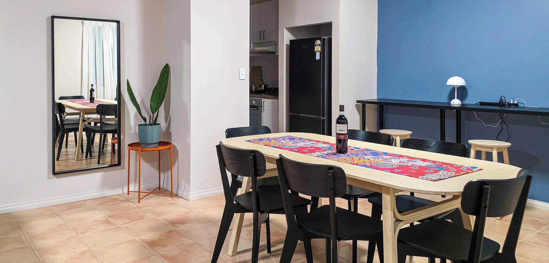 A dining area with a long table, black chairs, and a colorful table runner.