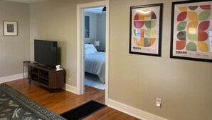 A hotel room with a television, framed artwork, and a bed. - Cozy Coach House: just minutes to CMU and Soaring Eagle Casino (Mount Pleasant)