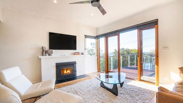 A modern living room with a fireplace, a flat-screen TV, and a balcony with a view. - Derwent Outlook Gateway to Scenic Trails and Beaches (Mount Nelson)