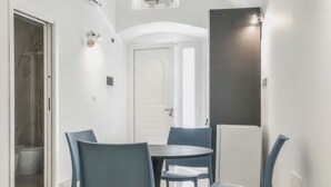Een modern interieur met een ronde tafel, vier stoelen, een witte deur en een koelkast.