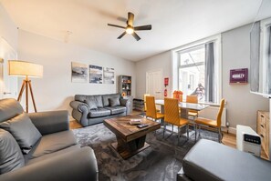 Ett modernt vardagsrum med en soffa, ett soffbord och en matplats med stolar.