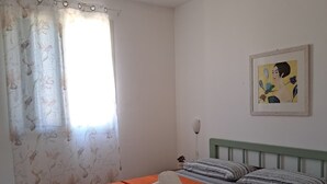 Et soveværelse med en seng, gardiner, et billede og en sengebordlampe.