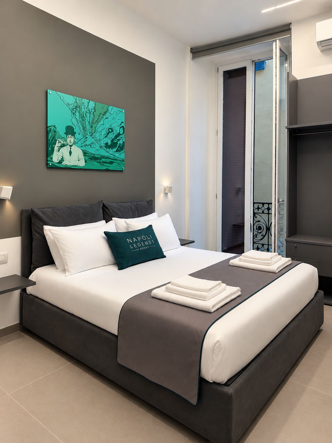 Una moderna camera d'hotel con un letto grande, un quadro appeso al muro e una porta scorrevole che dà su un balcone.
