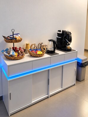 Een buffetopstelling met een koffiehoek, inclusief een koffiezetapparaat en manden met snacks.