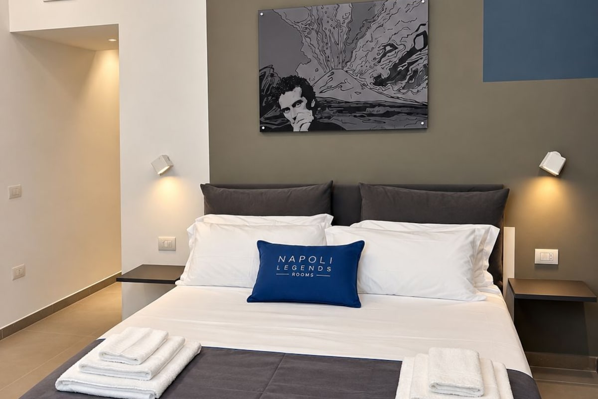 Een moderne hotelkamer met een groot bed, een schilderij aan de muur en twee bedlampjes.