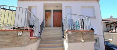 A two-story building with a central staircase, a door at the top, and a balcony on the upper floor.