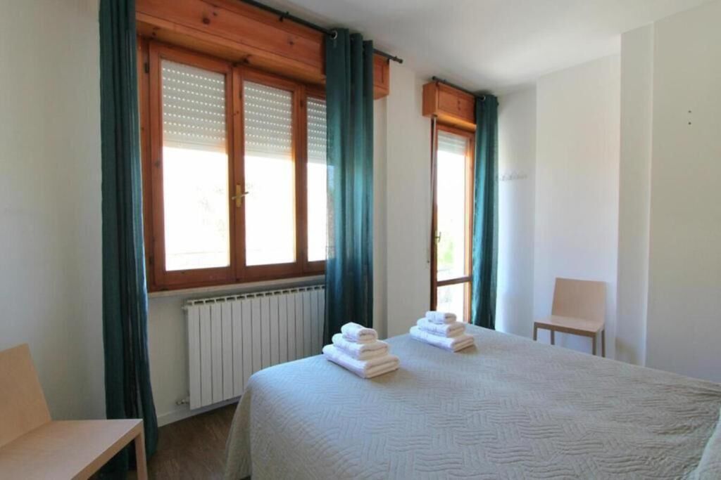 Una camera d'albergo con un letto, una sedia e una finestra con tende.