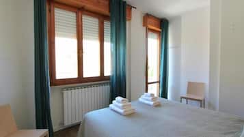 Una camera d'albergo con un letto, una sedia e una finestra con tende.