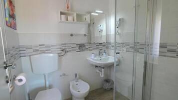 Driepersoonskamer | Badkamer | Een douche, een haardroger, handdoeken, zeep