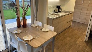 Eine moderne Küche mit Essbereich, einer Kaffeemaschine und Blick ins Freie.