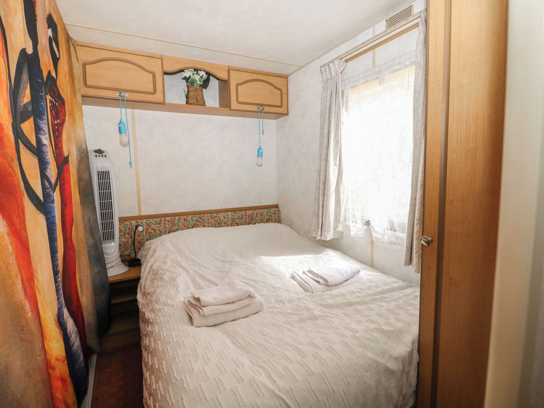A bedroom with a bed, a heater, a window with curtains, and a door.