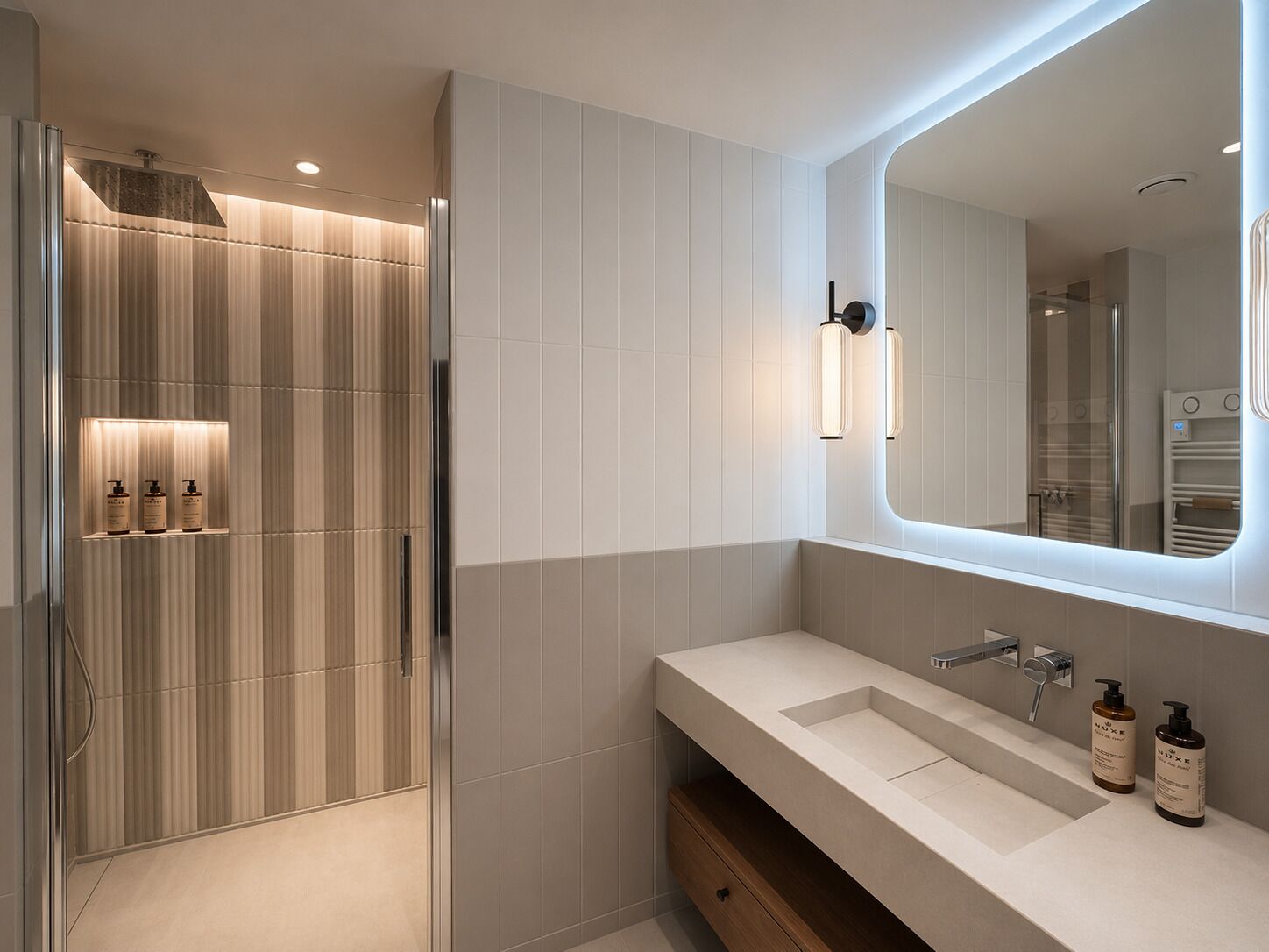 Une salle de bain moderne dotée d’une douche à l’italienne, d’un grand miroir et d’un meuble-lavabo avec un évier et des rangements.