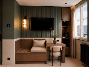 A modern living room with a sofa, a dining table, a chair, a TV mounted on a wall, and a window with curtains. - 336 Saint Honoré Hotel By Chapitre Collection (Paris)