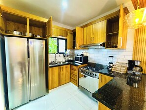 A kitchen with wooden cabinets, stainless steel appliances, a window, and a tiled backsplash. - 4tv Netflix Wifi hot Water air Conditioning (La Vega)