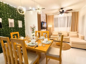 A modern living room with a dining area, a green wall, and a ceiling fan. - 4tv Netflix Wifi hot Water air Conditioning (La Vega)