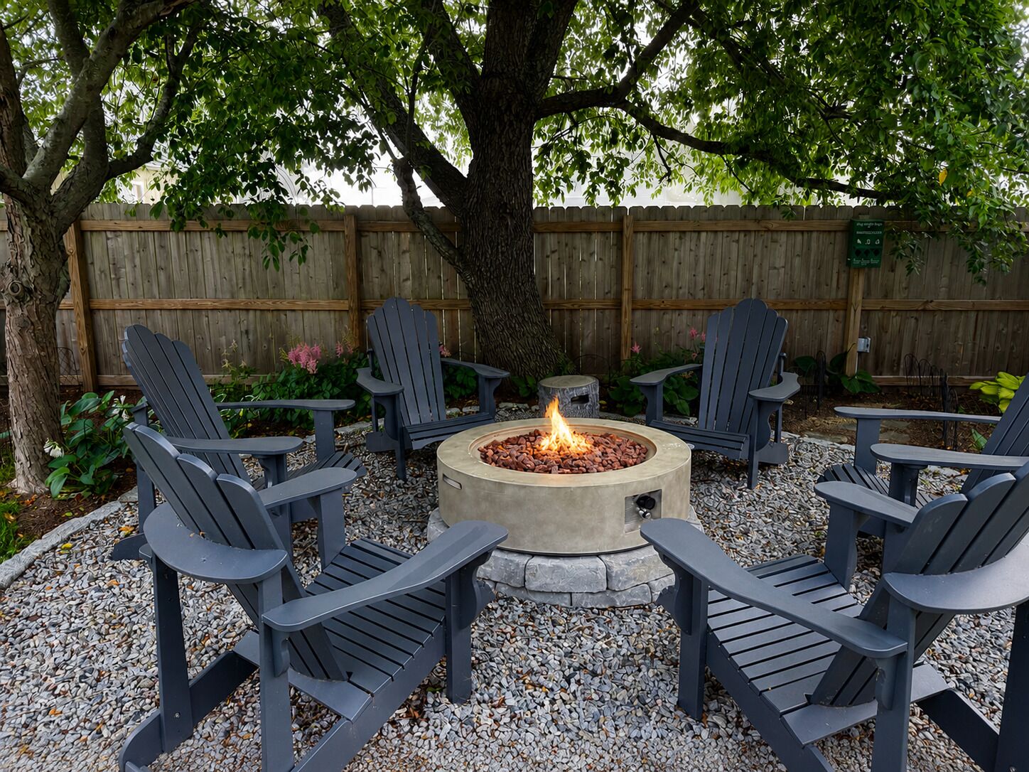A fire pit surrounded by Adirondack chairs in a backyard setting.