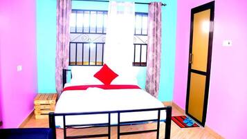 A room with a bed, a window with metal bars, a door, and a small wooden stool.