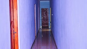 A hallway with blue walls and wooden flooring, leading to a door with a geometric pattern. - Safari Park House (Arusha)