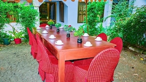 A wooden table with red checkered chairs, surrounded by potted plants. - Safari Park House (Arusha)