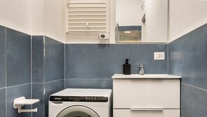 Ein modernes Badezimmer mit Waschmaschine, Waschbecken und Spiegel.
