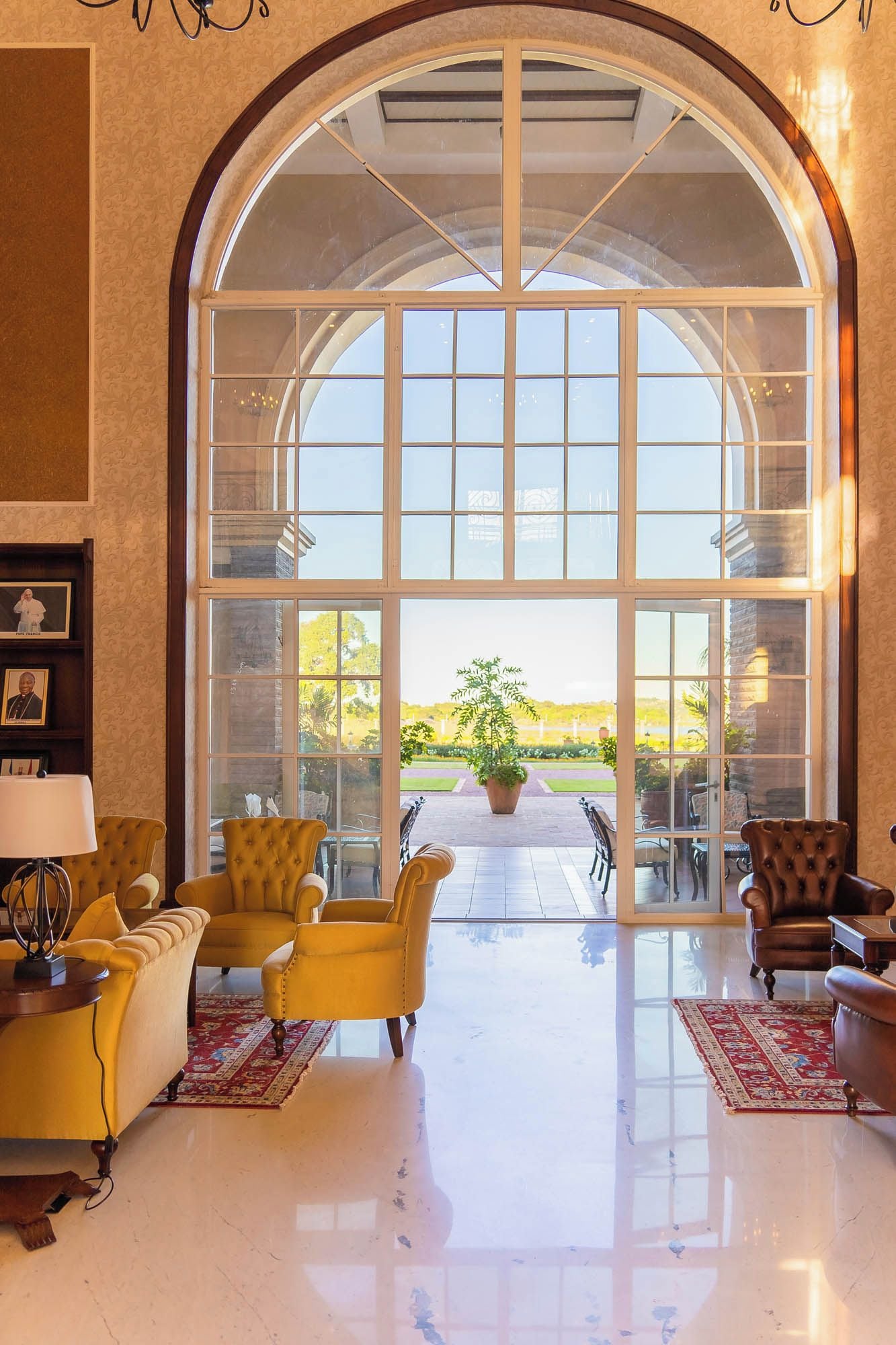 A spacious room with a large arched window, a fireplace, and comfortable seating.