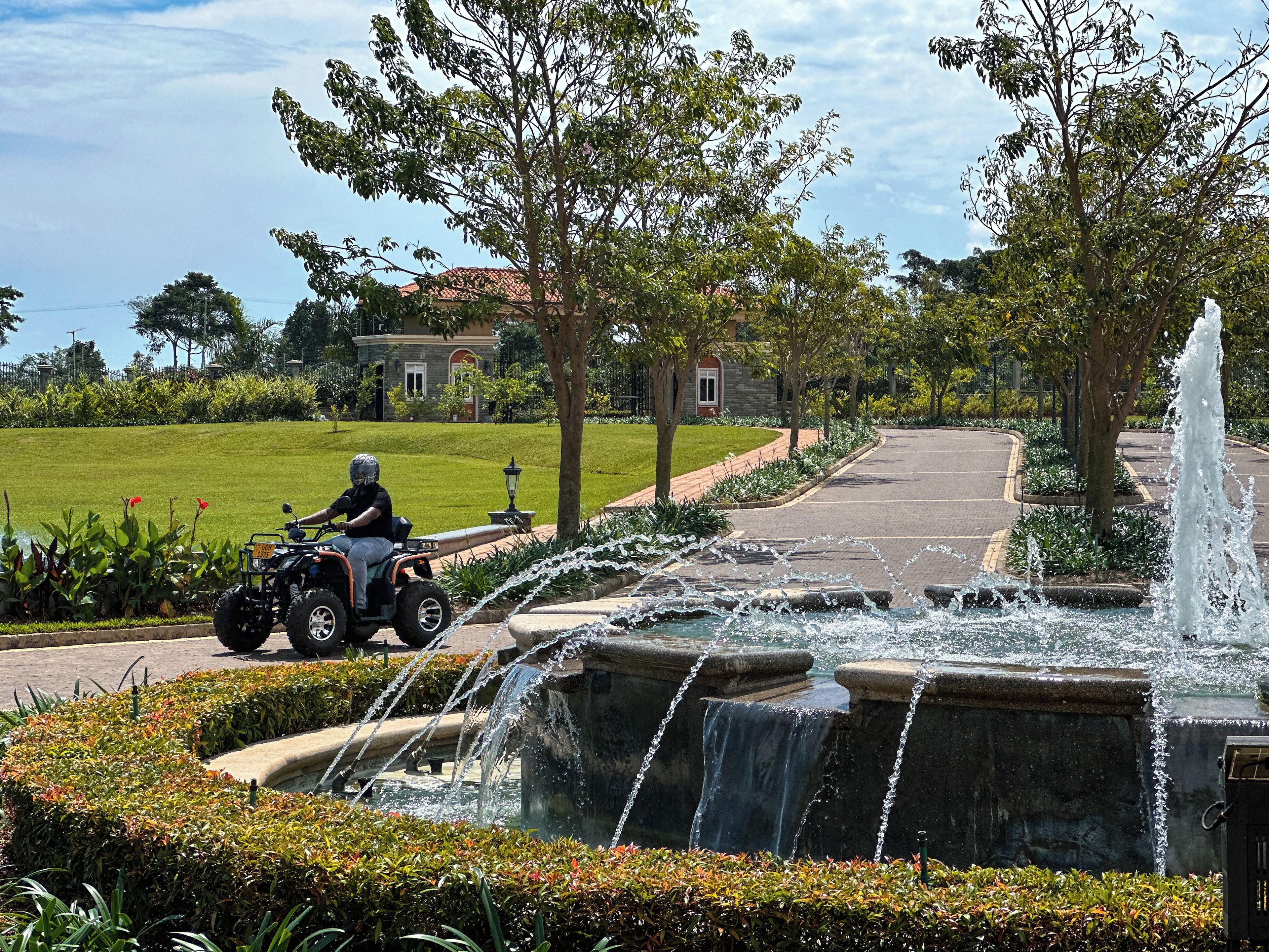 A paved pathway with a water feature and a person riding an ATV.