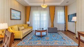 A hotel room with a sofa, ottoman, round coffee table, and a large rug. - Avellino Lakeside Escape (Entebbe)