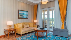 A hotel room with a sofa, a round coffee table, a side table, a lamp, a painting, and a view through a glass door. - Avellino Lakeside Escape (Entebbe)
