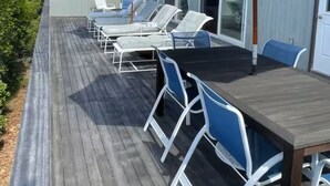 A deck with outdoor seating, a table, and a large umbrella.
