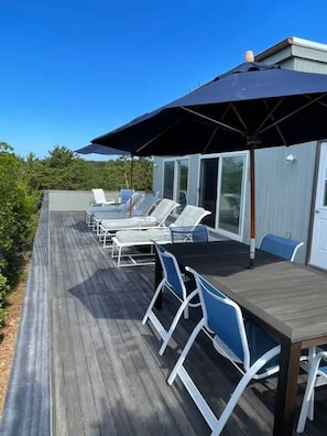 Eine Terrasse mit Sitzgelegenheiten im Freien, einem Tisch und einem großen Sonnenschirm.