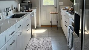 A modern kitchen with white cabinetry, a built-in oven, a stainless steel refrigerator, and a window with a view.