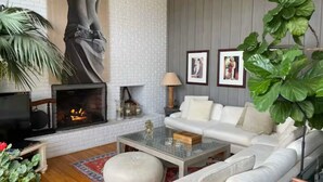 A living room with a fireplace, white sofa, and large green plant.
