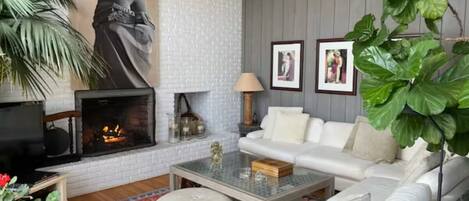 A living room with a fireplace, white sofa, and large green plant.