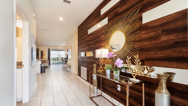 A modern hallway with a wooden accent wall, a glass console table, and a decorative mirror. - 8886-CabotCliffs (Kissimmee)