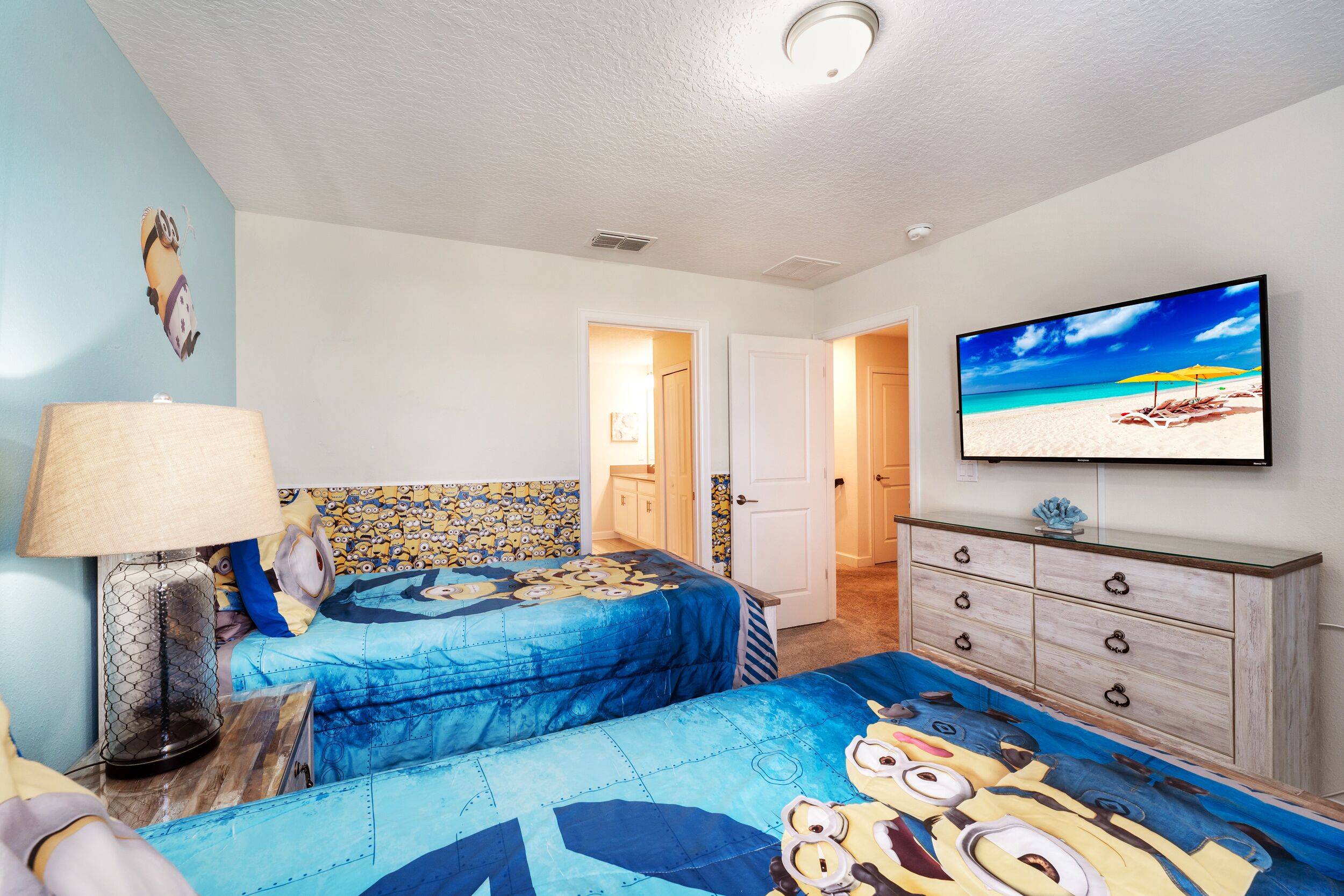 A bedroom with two beds, a TV, a dresser, and a lamp.
