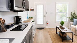 Una cucina moderna con forno a microonde, macchina del caffè e zona pranzo con divano e una pianta.