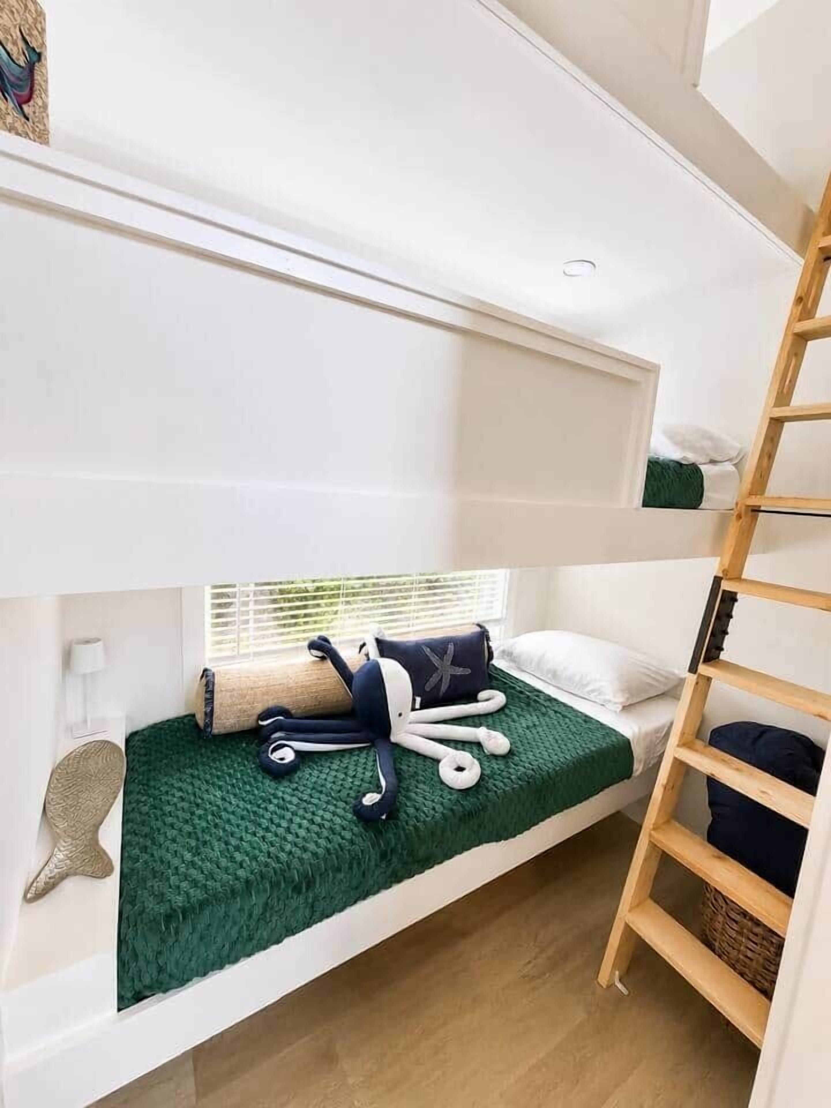 A bunk bed with a green blanket, a starfish decoration, and a wooden ladder.
