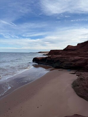 Une plage bordée d’un rivage rocheux et baignée par une mer calme.