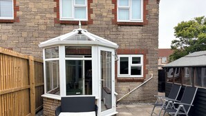 A conservatory with a bench, a wooden fence, and a stone wall.