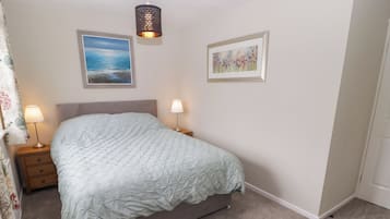 Un dormitorio con cama, dos lámparas de noche, un cuadro enmarcado y una lámpara de pared.
