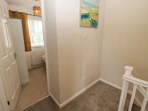 A hallway with a white door, a radiator, a painting on the wall, and a white railing.